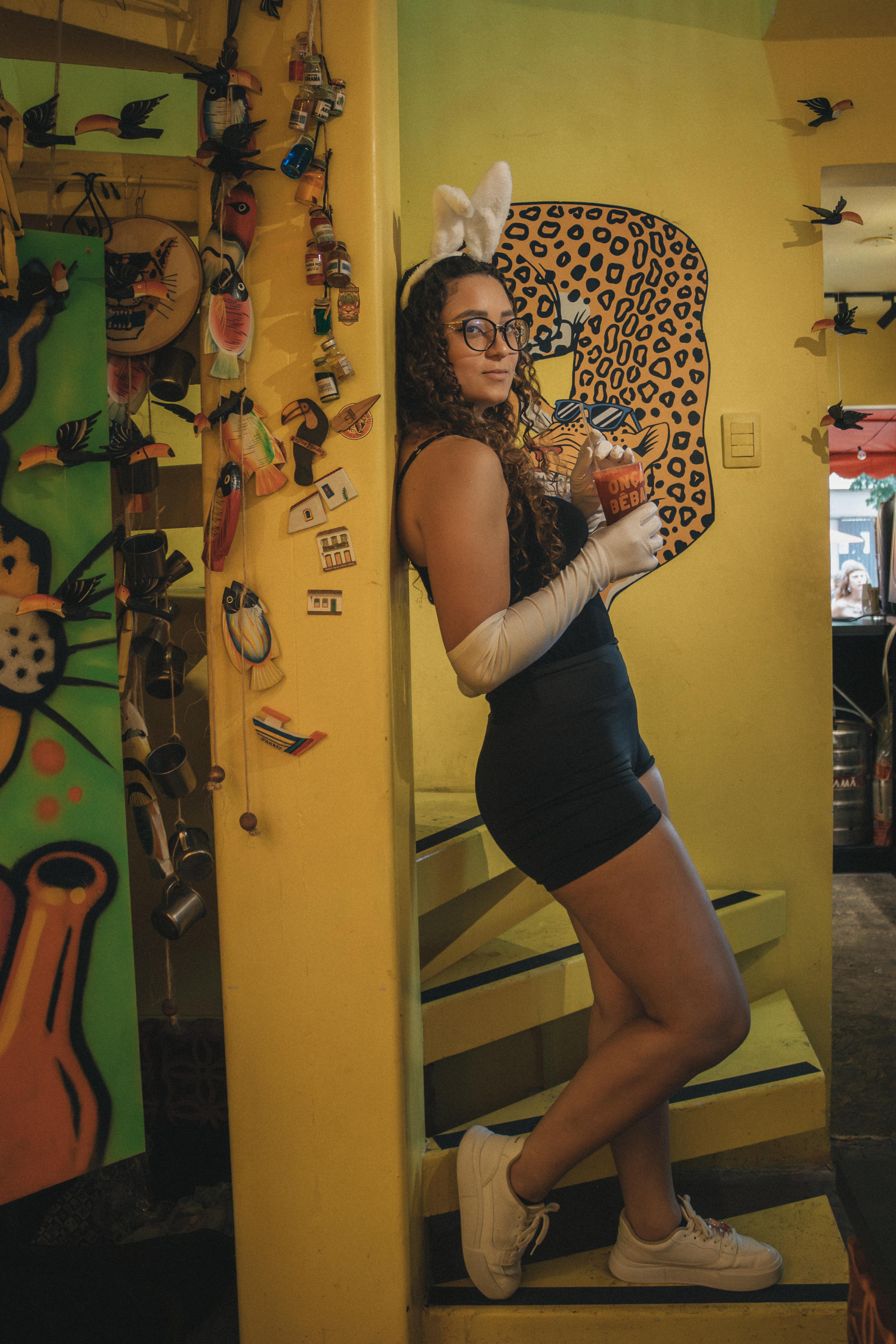 ingyenes Egy stílusos nő nyuszifülekkel és egy koktéllal egy színes, művészi belső környezetben. Stockfotó