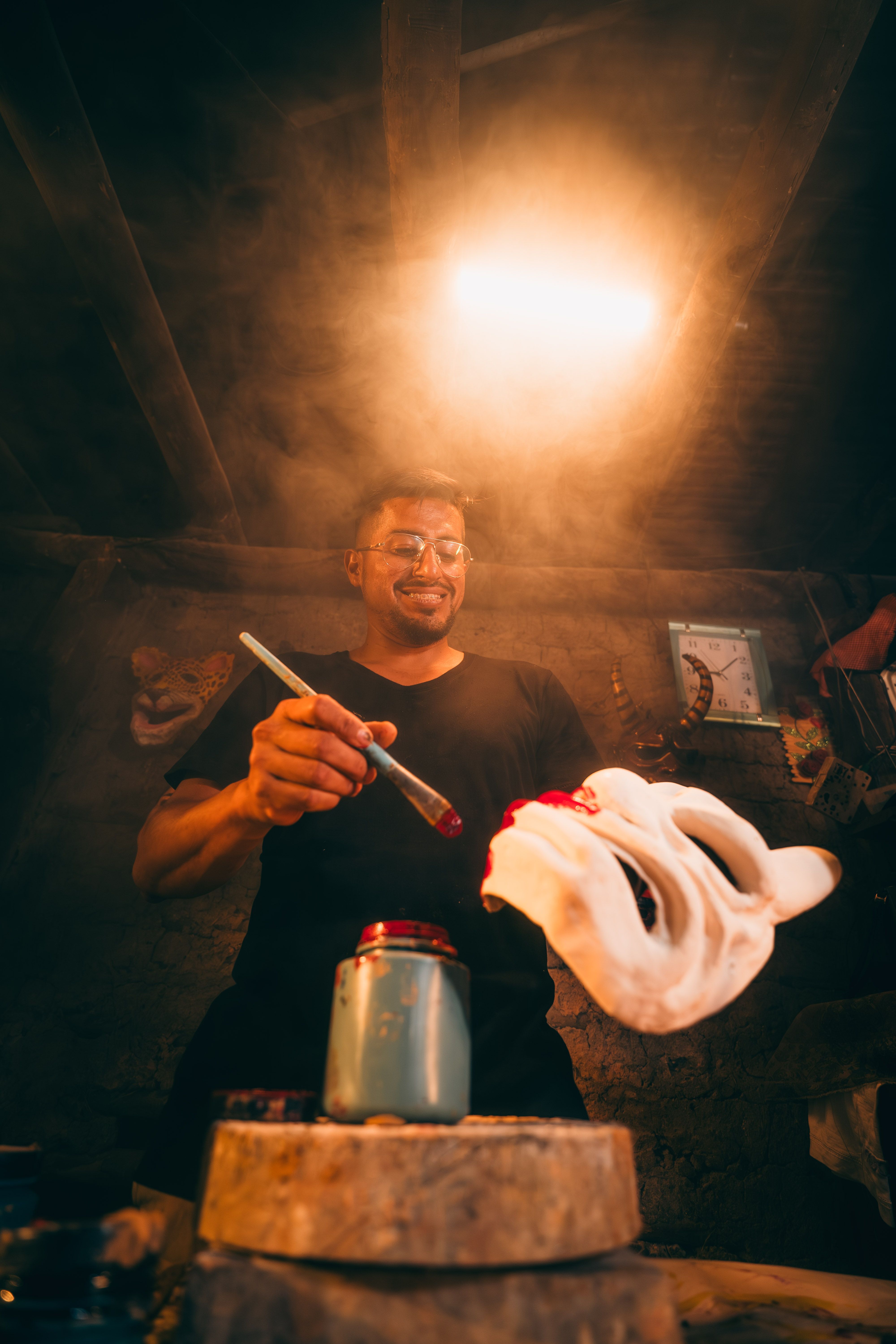 A Peruvian artisan painting a mask in a dimly lit workshop, showcasing cultural craftsmanship.