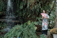 Woman in Traditional Dress by Waterfall in Lush Forest