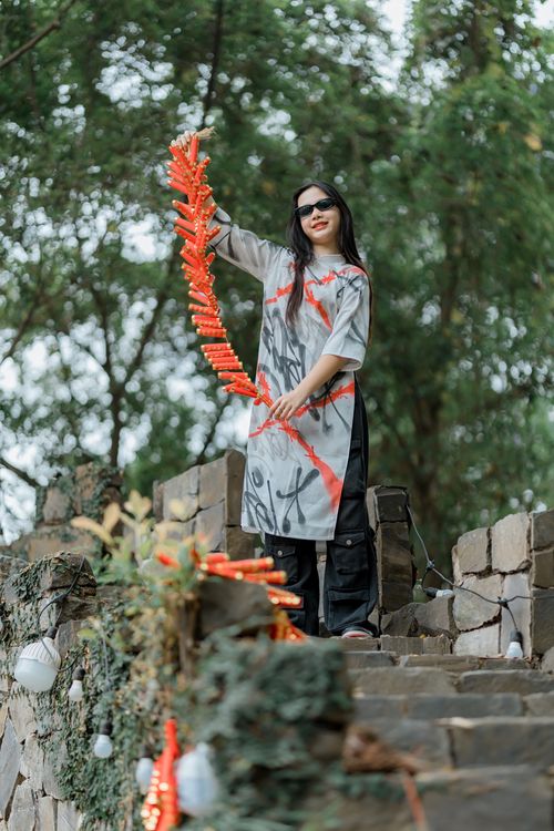Free Woman in stylish outfit holding firecrackers outdoors, joyful celebration. Stock Photo