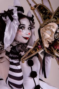 Colorful harlequin costume with intricate makeup and ornate mask, captured with dramatic lighting.