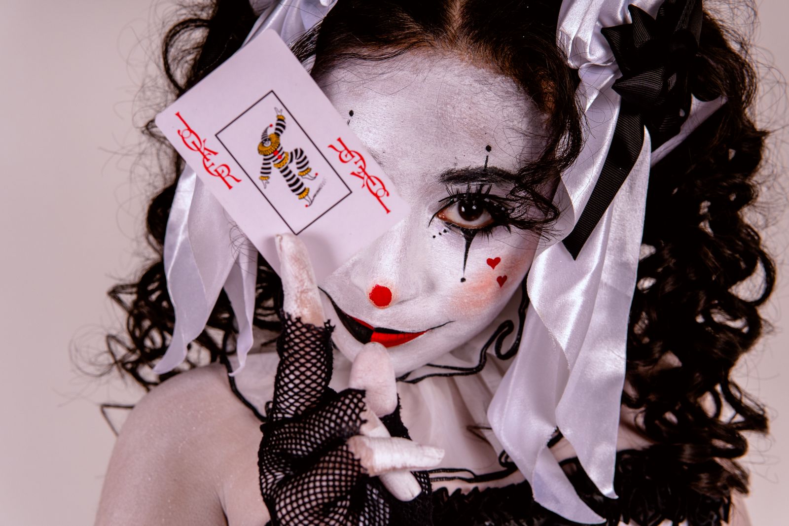 Visage maquillé en Joker avec peau pâle, cicatrices Glasgow smile rouges et yeux noirs charbonneux