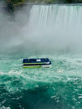 A tour boat sails near the breathtaking Niagara Falls surrounded by mist and swirling waters.