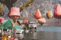 在奥地利哈尔施塔特宁静的湖面上，色彩缤纷的灯笼悬挂着，背景是乡村的船库