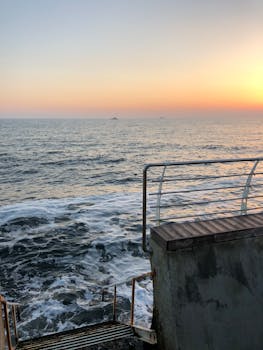 Tranquil sunset view over the Black Sea with waves and a seaside railing in Odesa, Ukraine.