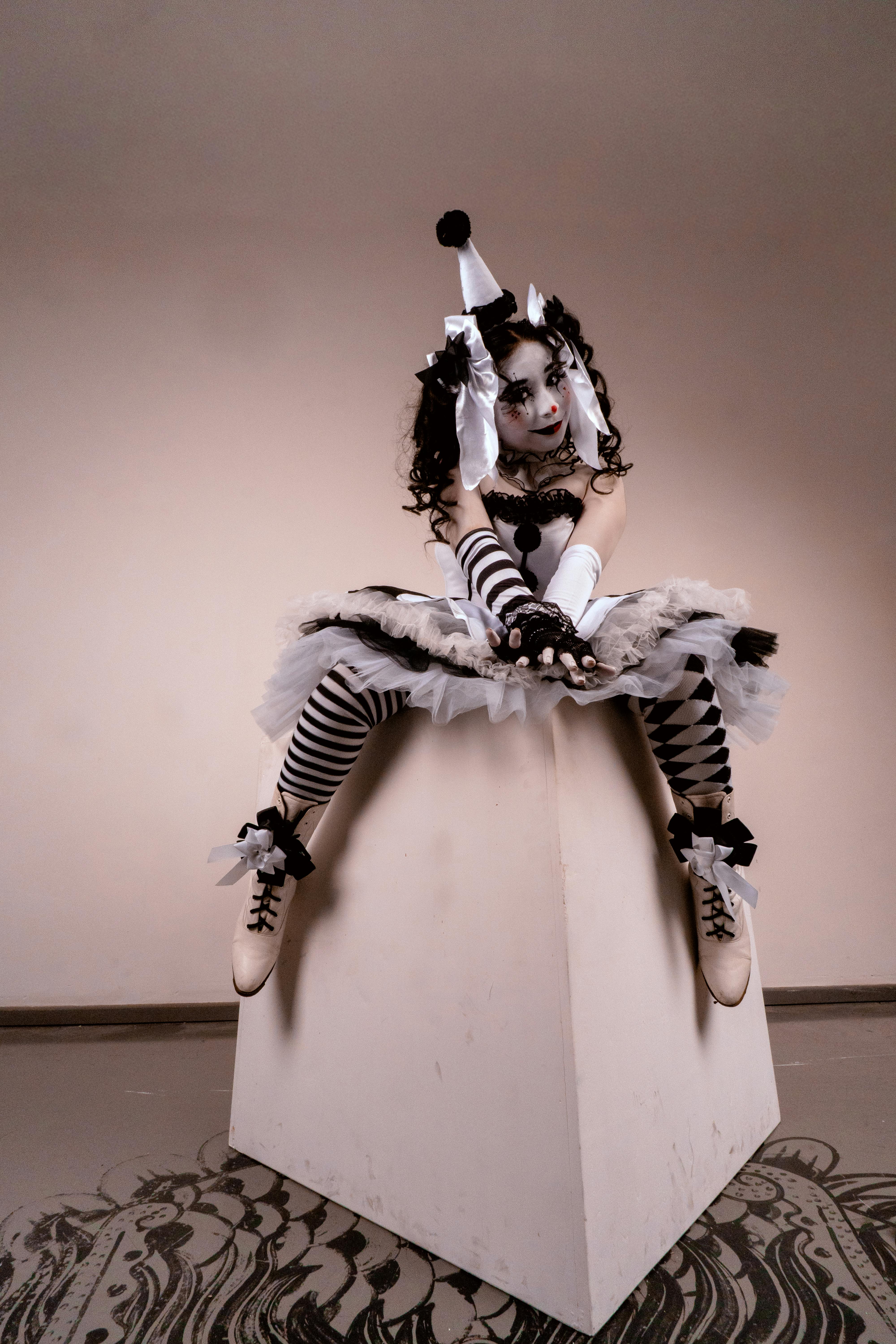 ฟรี หญิงชาวละตินคนหนึ่งโพสท่าในชุดและแต่งหน้าตัวตลกที่ประณีต นั่งอยู่ภายในบ้าน คลังภาพถ่าย