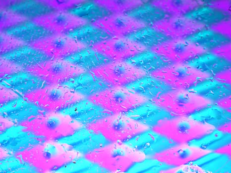 Colorful abstract pattern with pink and blue neon hues and water droplets.