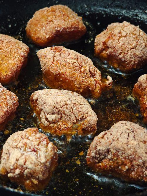 Seasoned chicken pieces frying in hot oil in the MO's kitchen