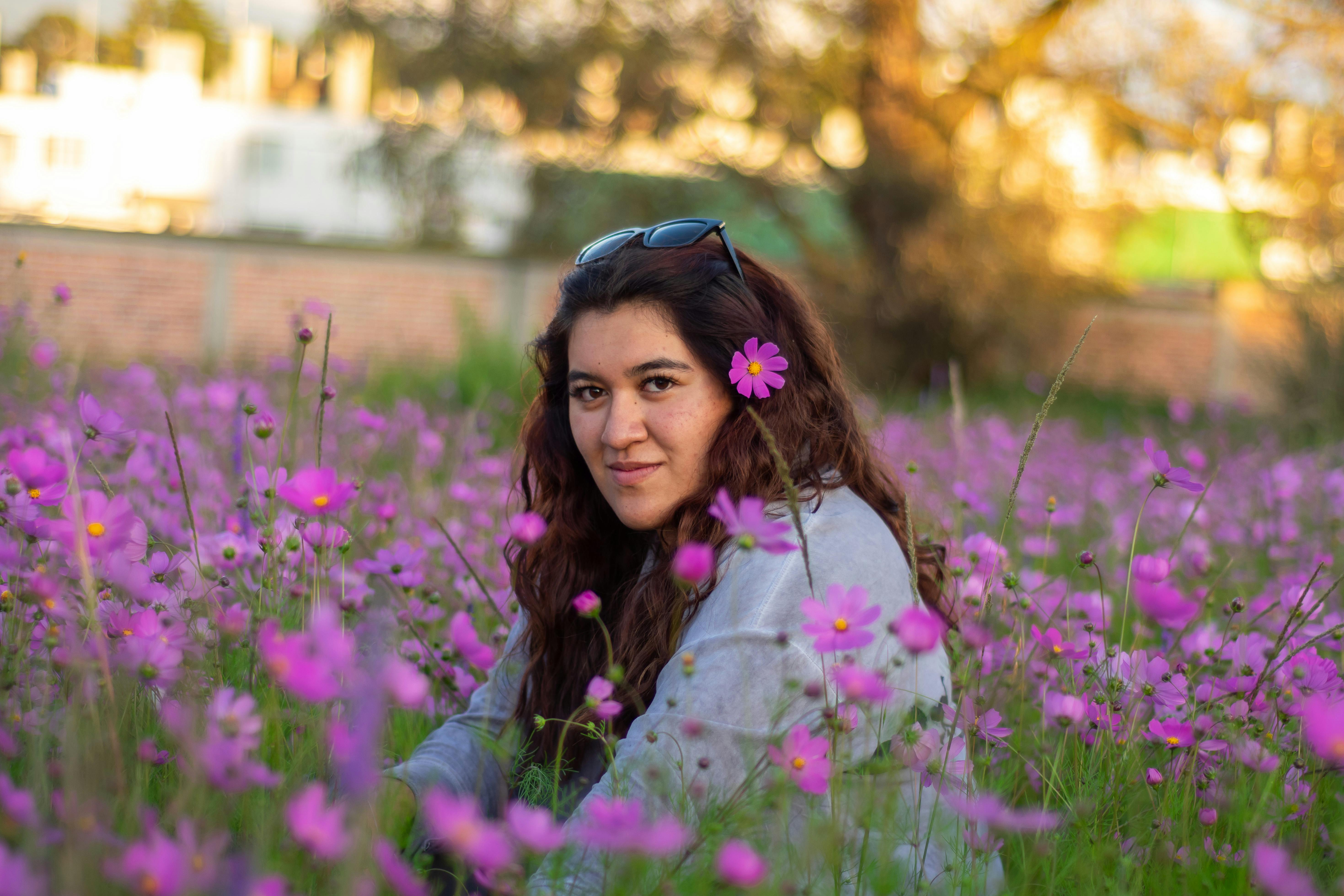 A serene portrait of a woman sitting in a field of pink flowers in Lerma, Mexico, at sunset.