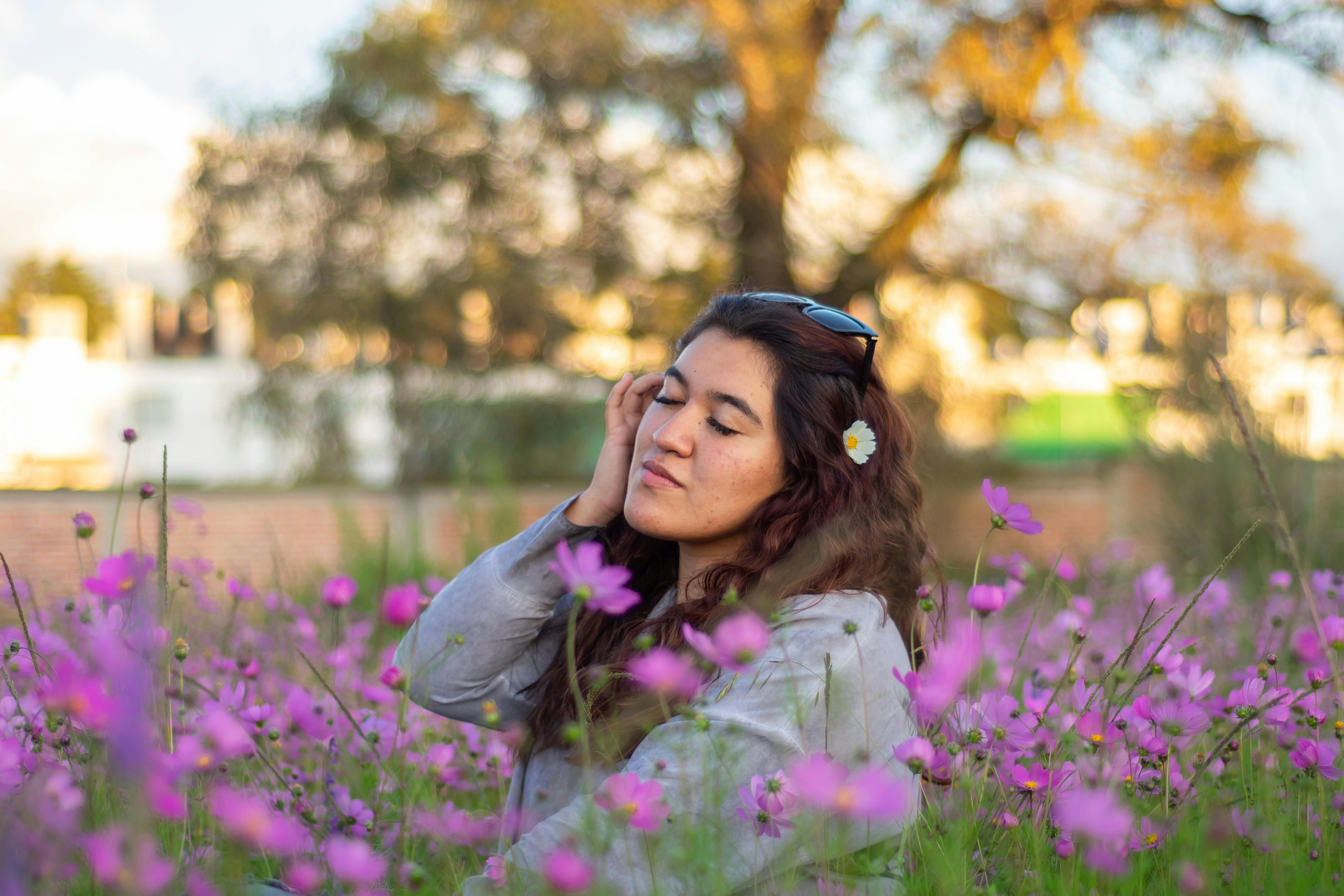 Young woman enjoying a moment in a field of vibrant purple cosmos flowers.