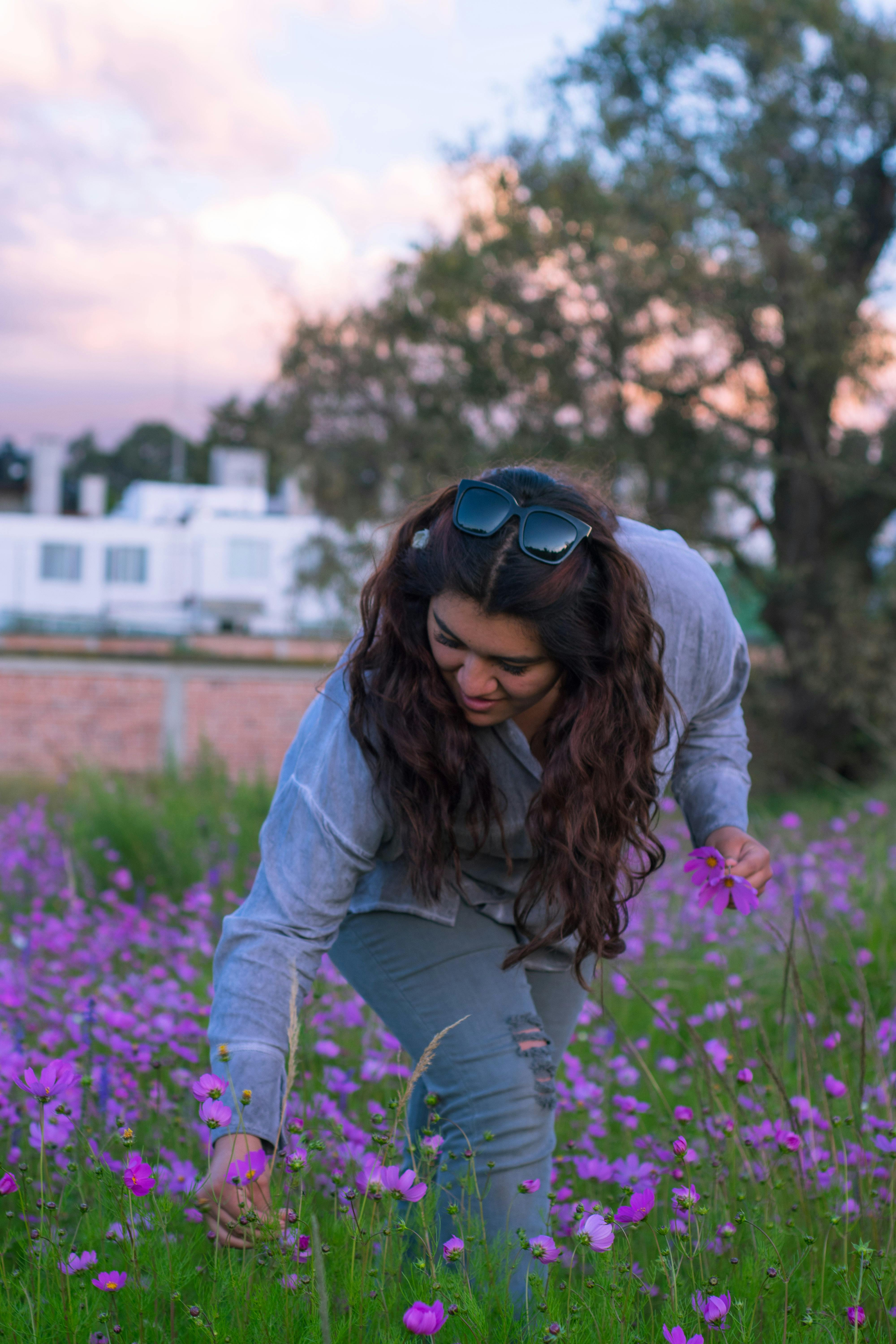 A woman admires colorful purple wildflowers in a scenic field in Lerma de Villada, Mexico at sunset.