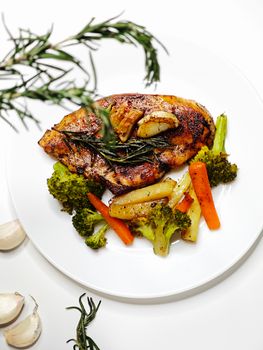 Flavorful grilled chicken breast served with fresh vegetables on a white plate.