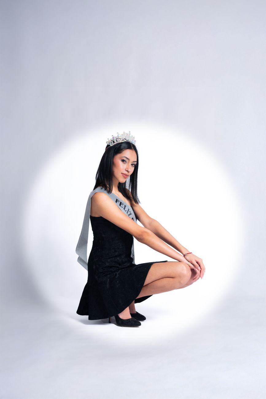 Young woman celebrating her birthday with a crown and sash in a studio portrait.