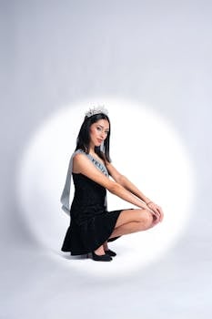 Young woman celebrating her birthday with a crown and sash in a studio portrait.