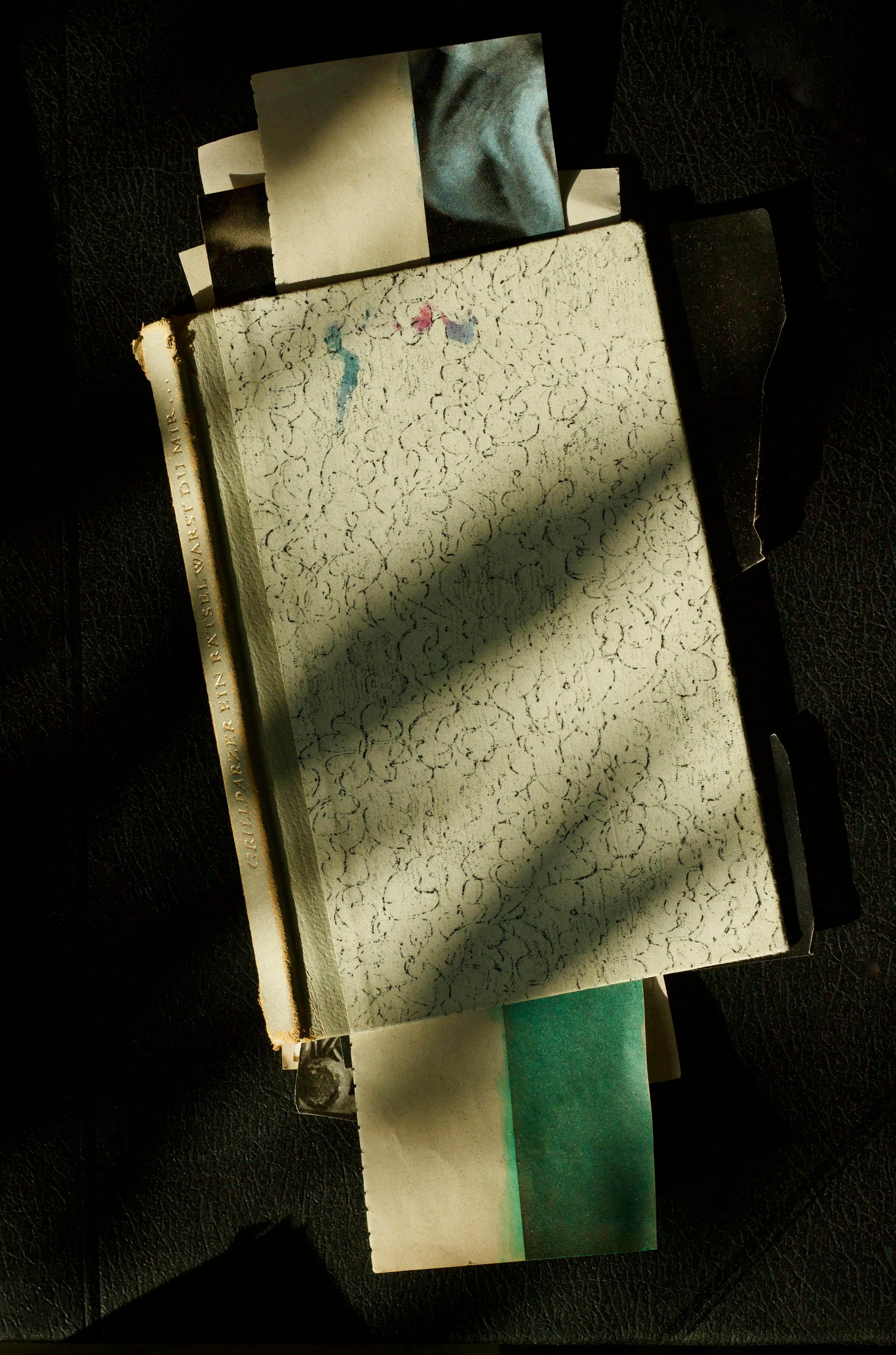 Free A creatively arranged stack of papers and sketchbook with artistic shadows, offering a vintage feel. Stock Photo