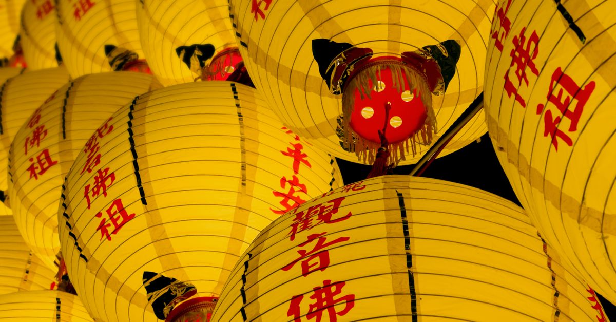 Bright yellow lanterns with red Chinese characters symbolize good fortune during a festival celebration.