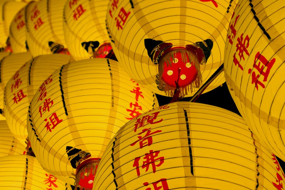 Bright yellow lanterns with red Chinese characters symbolize good fortune during a festival celebration.