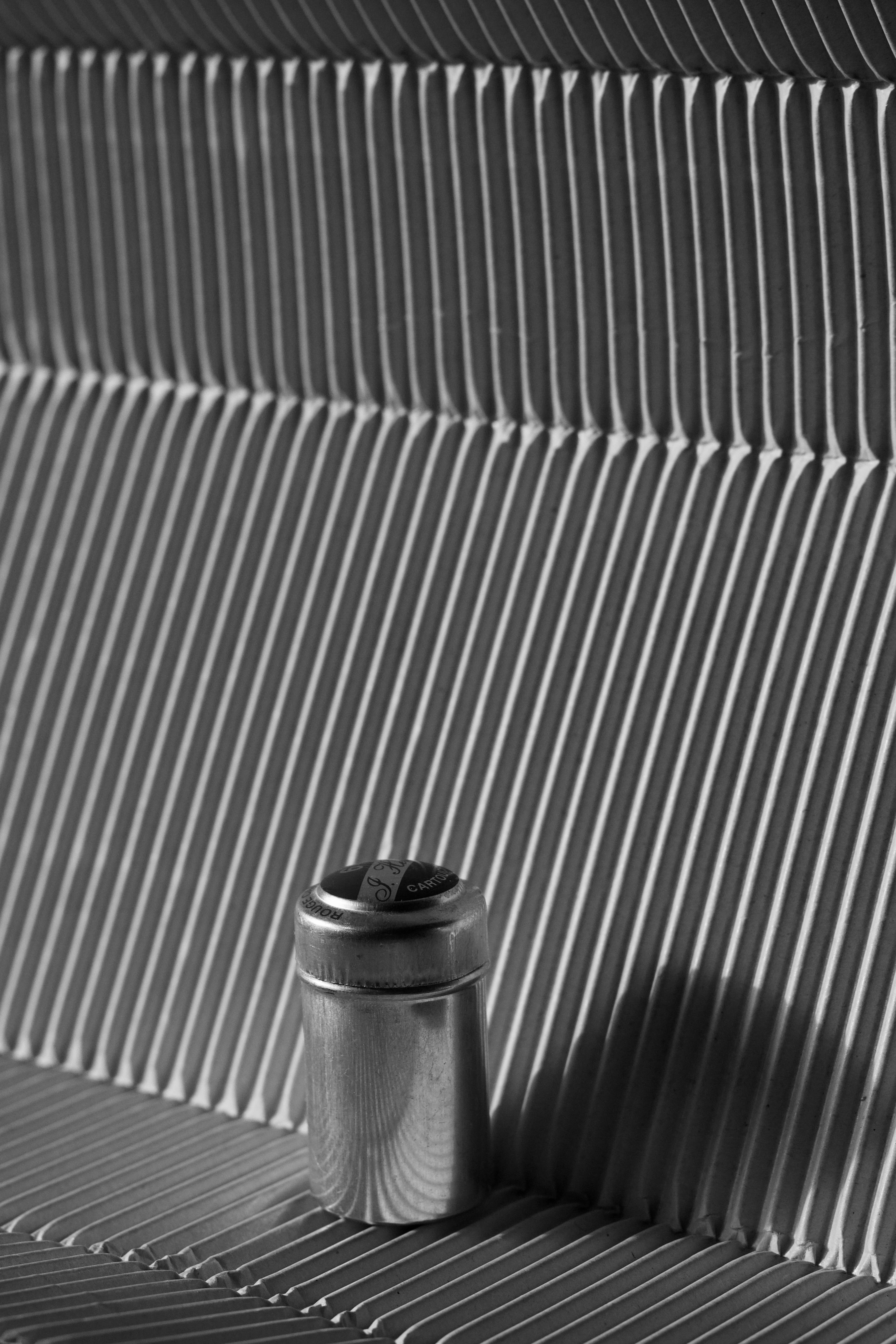 Free Elegant black and white photo of a stainless steel canister on a modern, textured surface. Stock Photo