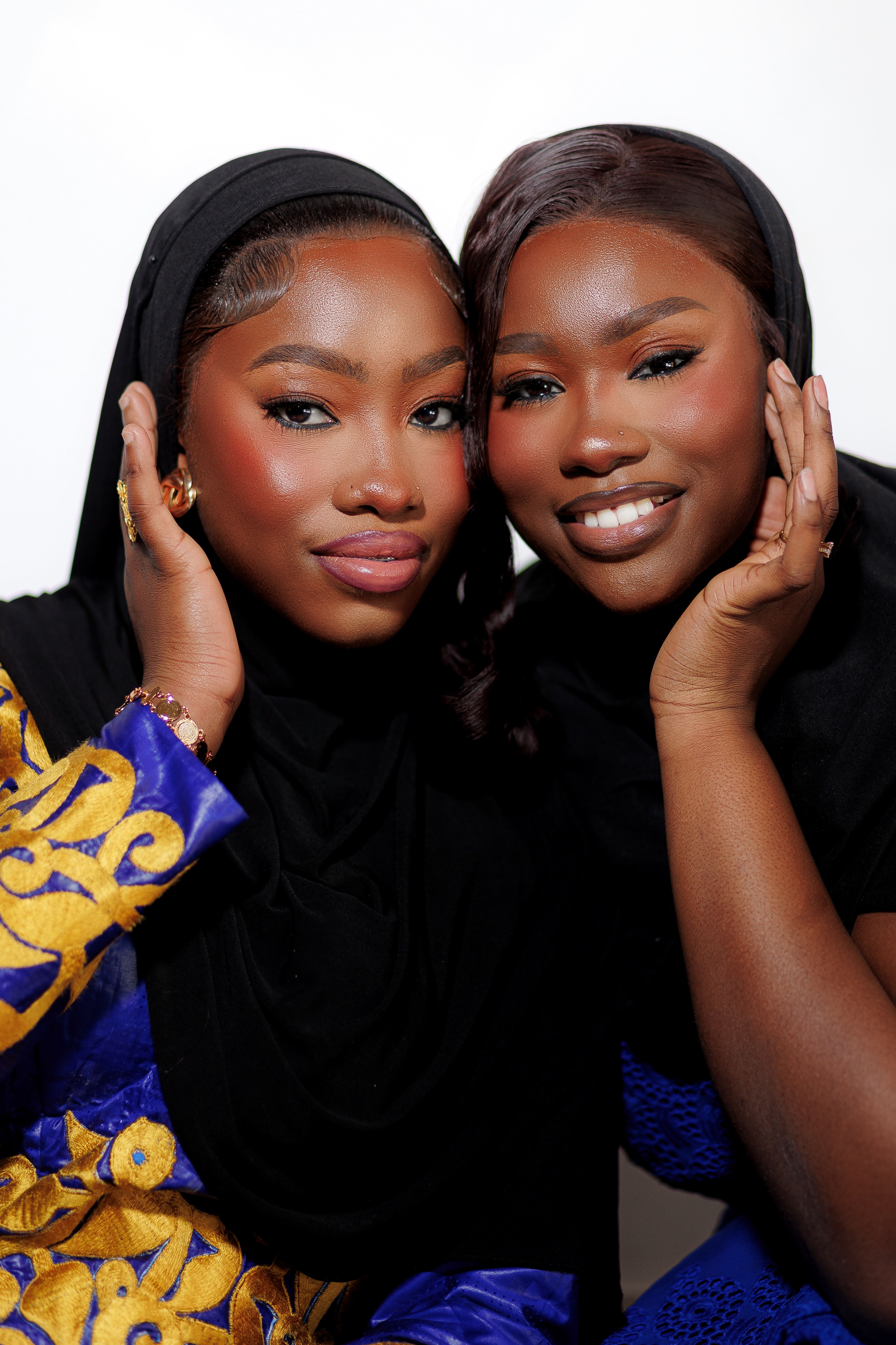 Close-up portrait of two women in vibrant traditional clothing and headscarves, smiling warmly.