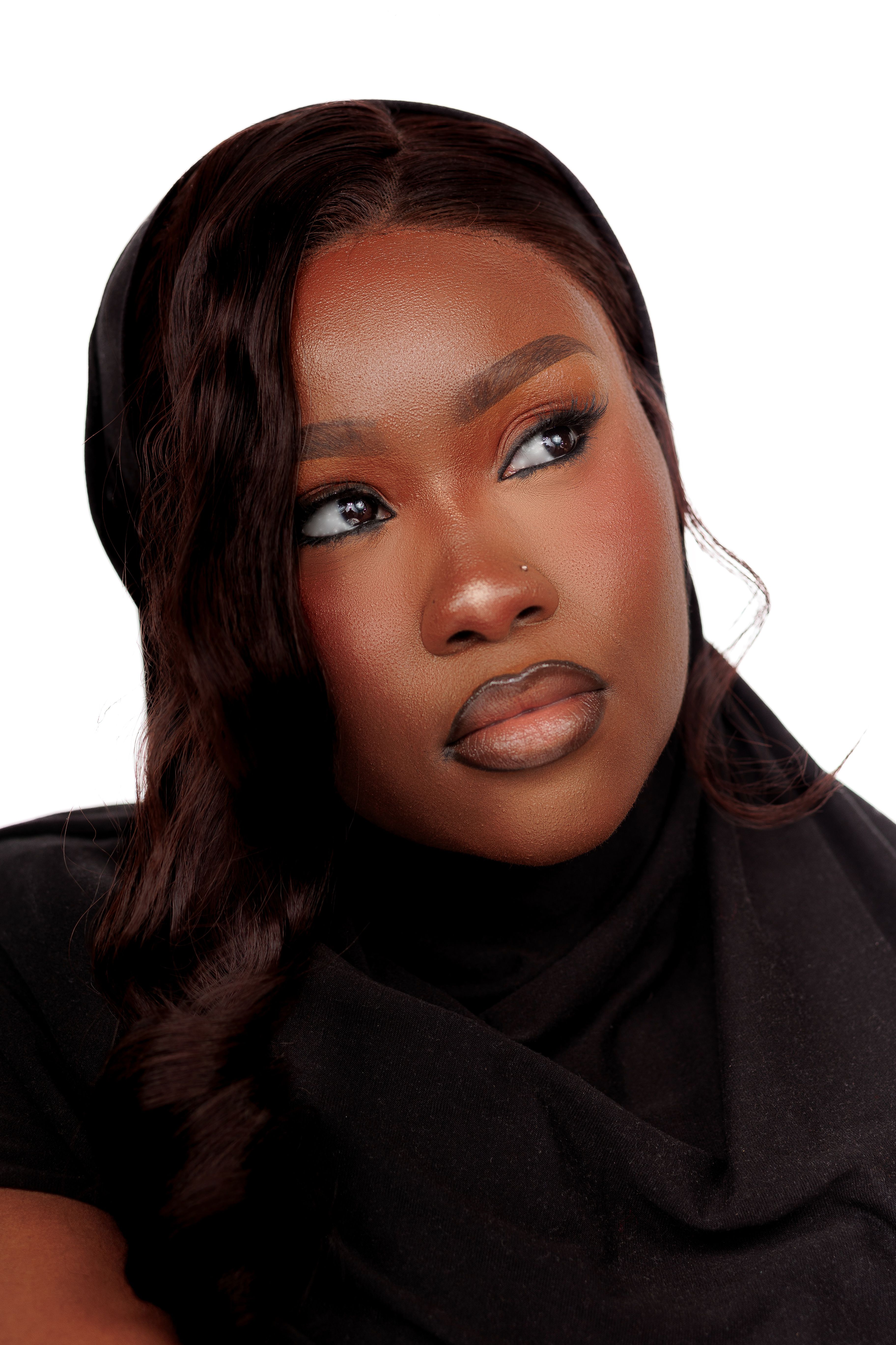 Close-up portrait of a woman wearing a black headscarf and elegant makeup, looking thoughtfully to the side.