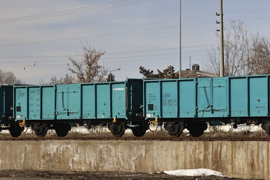 A bright turquoise freight train sits on rail tracks outdoors, showcasing industrial bold design.