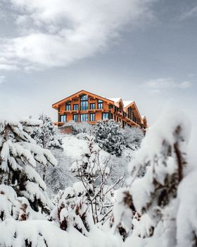 A picturesque mountain resort surrounded by snow-covered trees under a cloudy sky in Uzbekistan.