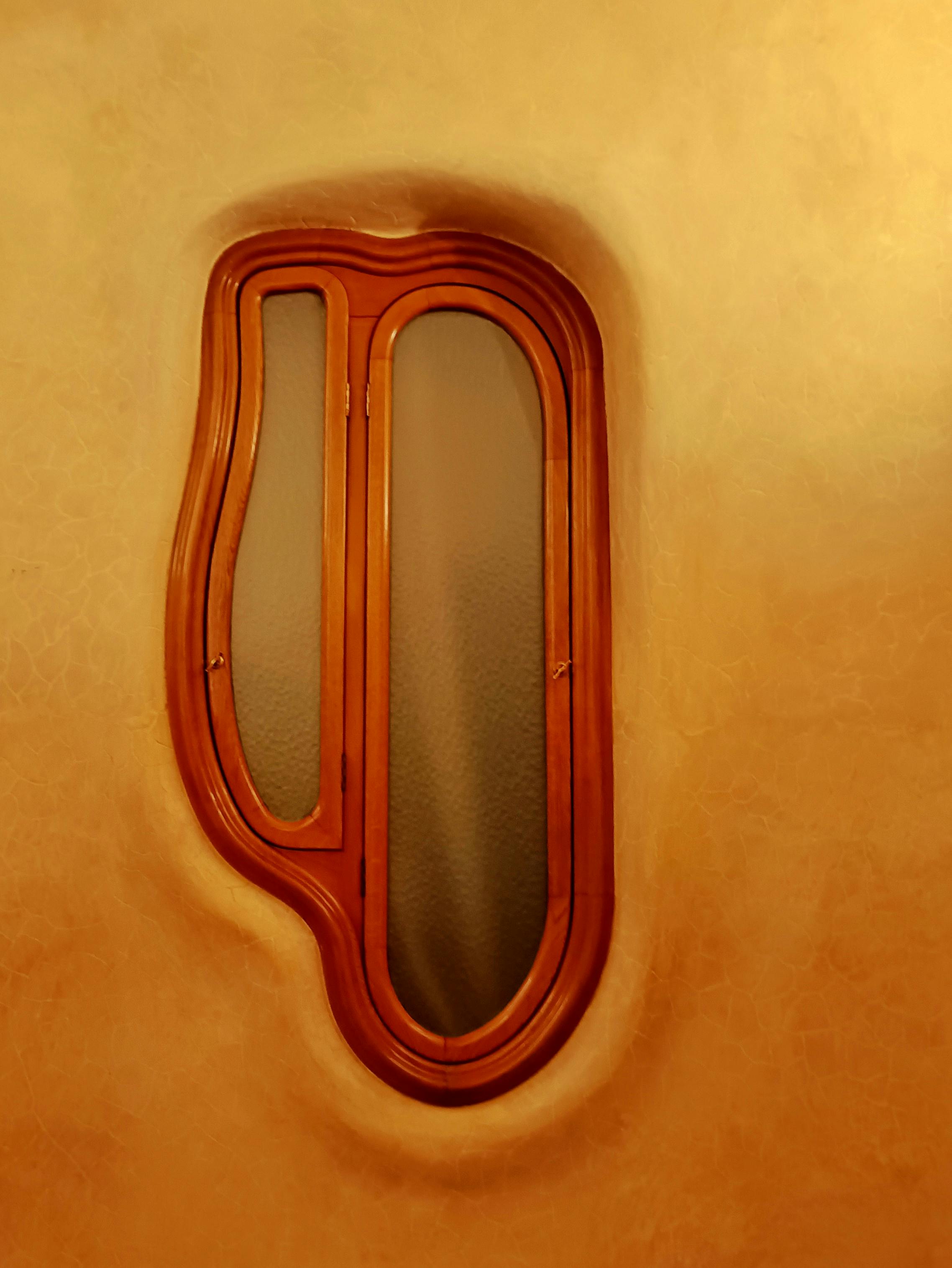 Free Unique wooden window with organic curves set in a textured wall, showcasing artistic architectural design. Stock Photo