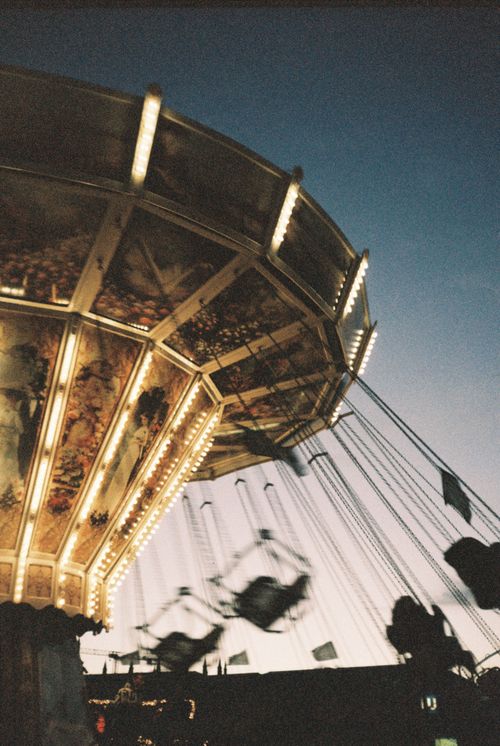 Free A beautifully illuminated vintage swing carousel spins at twilight in Berlin, Germany. Stock Photo