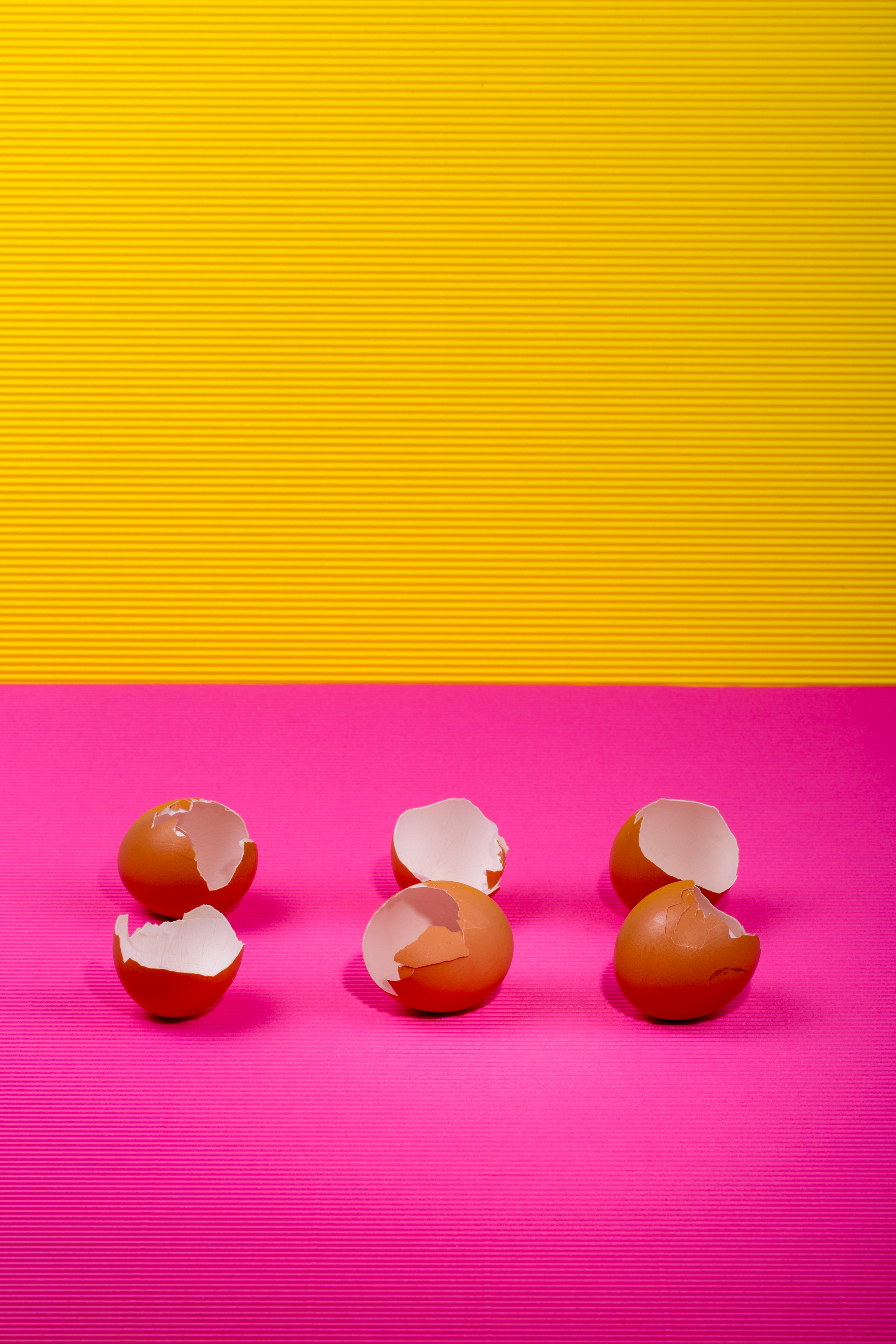 Free Six brown eggshells on pink and yellow background with vivid colors. Stock Photo
