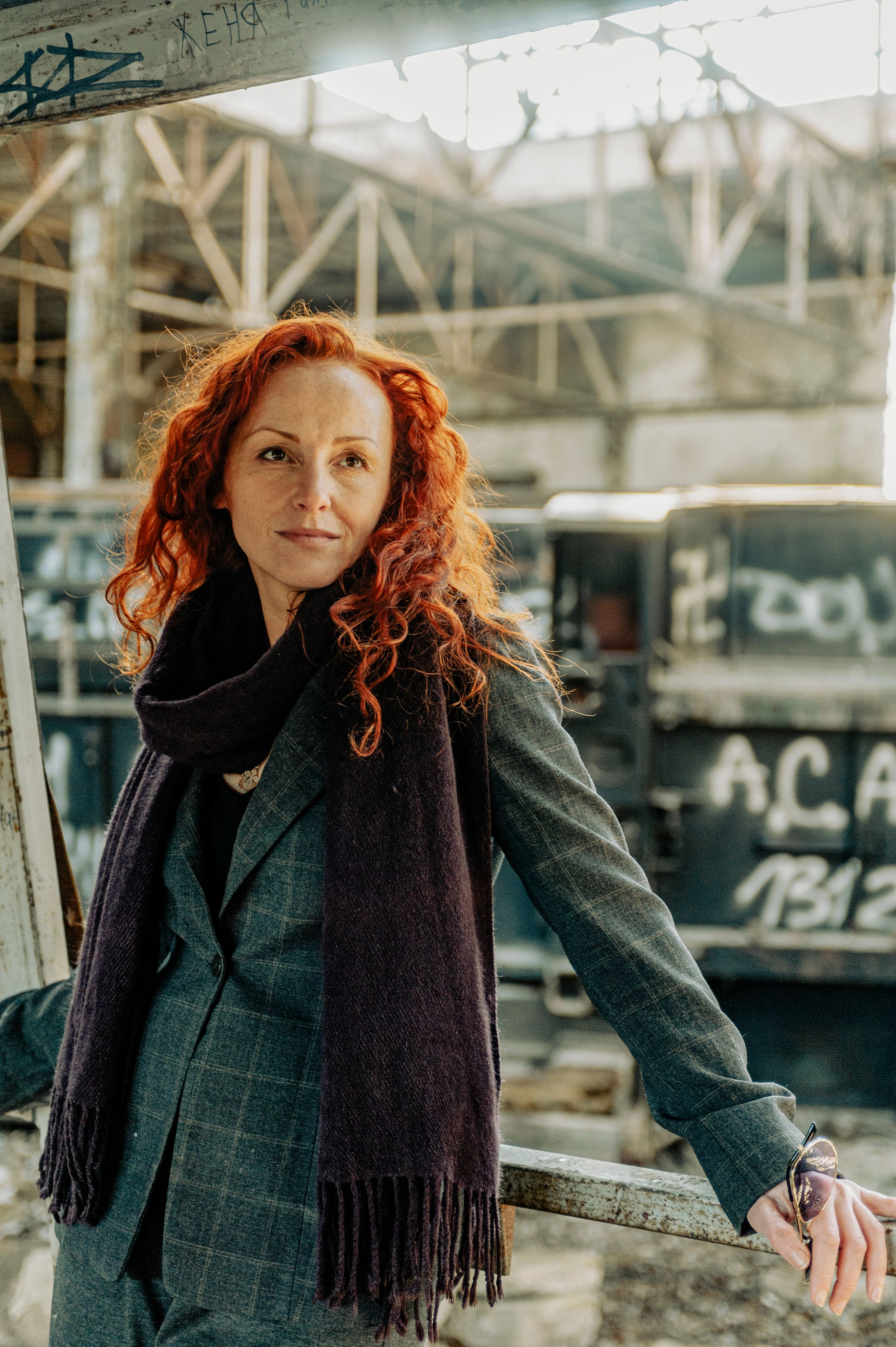 Portrait of a red-haired woman in a suit standing in an industrial area in Lviv, Ukraine.