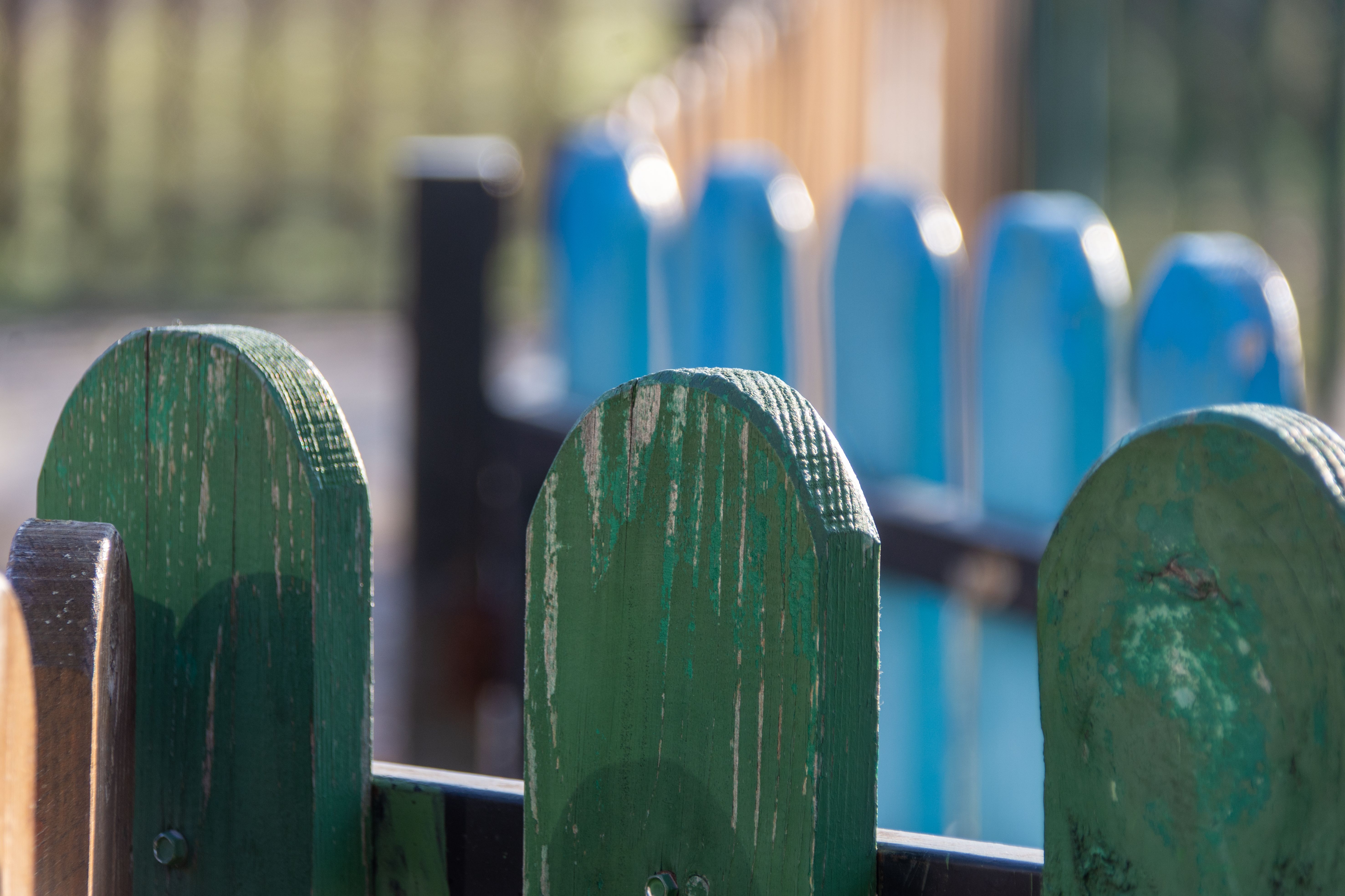 Close-up of a colorful wooden fence with green and blue slats, set outdoors.