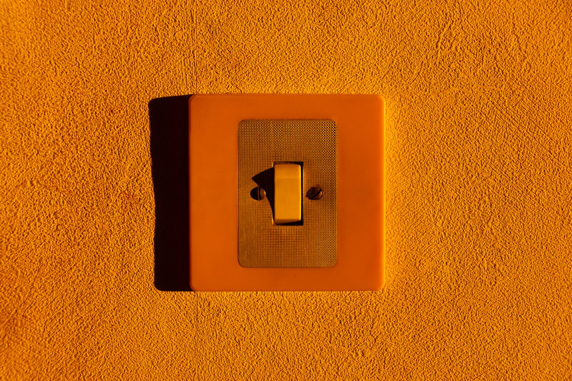 Close-up of a yellow light switch on a textured wall, highlighting minimalism.