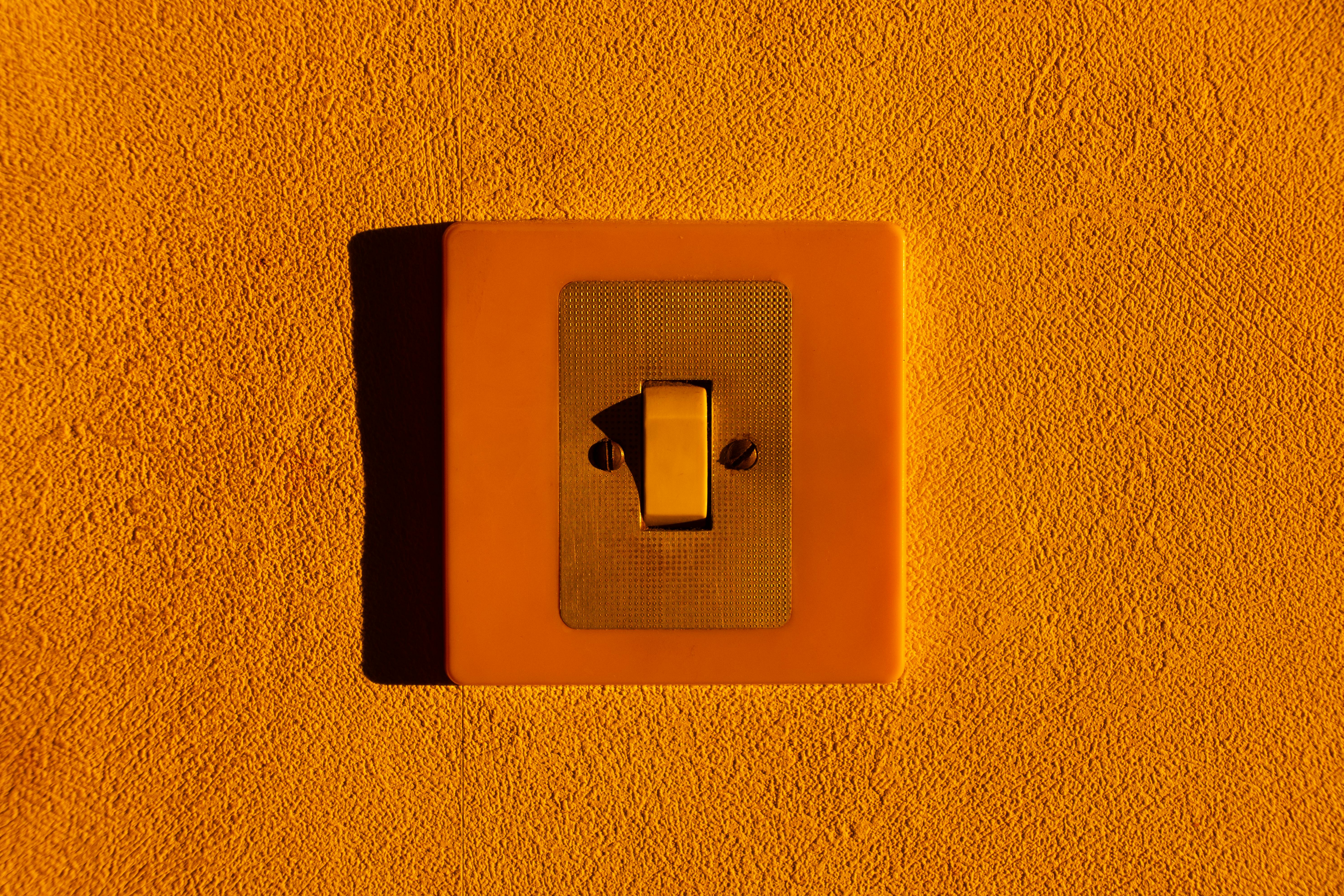 Free Close-up of a yellow light switch on a textured wall, highlighting minimalism. Stock Photo