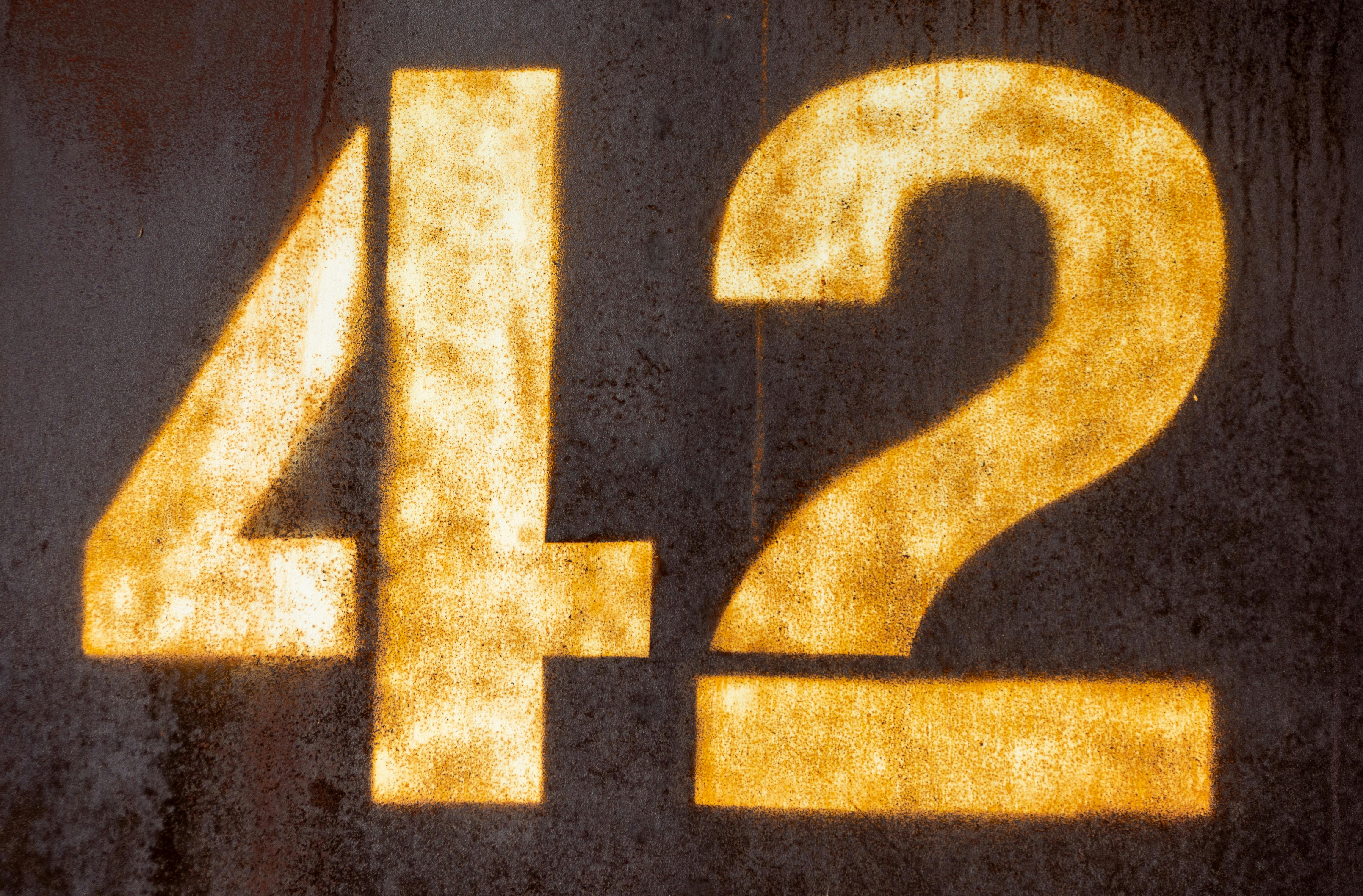 Free Textured grunge number 42 painted in bright yellow on an aged metal surface. Stock Photo