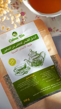 High-angle shot of herbal tea blend packaging next to a cup of tea.
