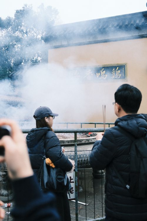 Free Visitors at a historical temple in Nanjing with incense smoke creating a mystical atmosphere. Stock Photo