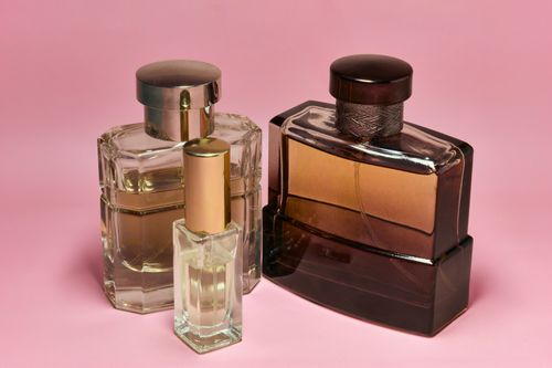Free Three stylish perfume bottles with elegant caps on a pink backdrop, capturing a sense of luxury and sophistication. Stock Photo