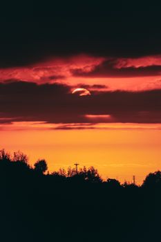 Captivating view of a radiant sunset with dramatic clouds and silhouetted trees.