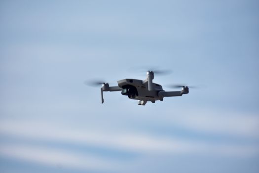 A drone effortlessly glides through the clear blue sky, showcasing modern aerial technology.