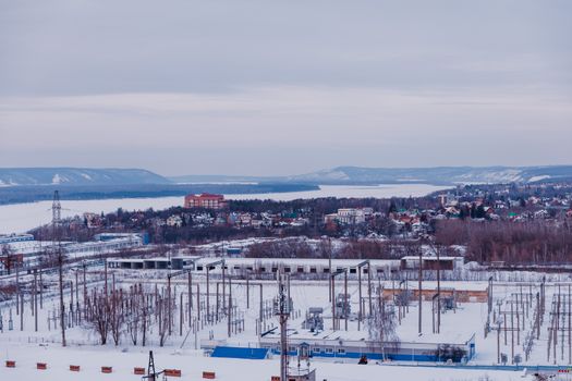 Snow-covered suburban landscape with power lines and distant hills.
