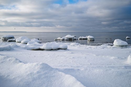 Free A serene winter seascape in Estonia featuring snow-covered icy rocks and calm waters. Stock Photo
