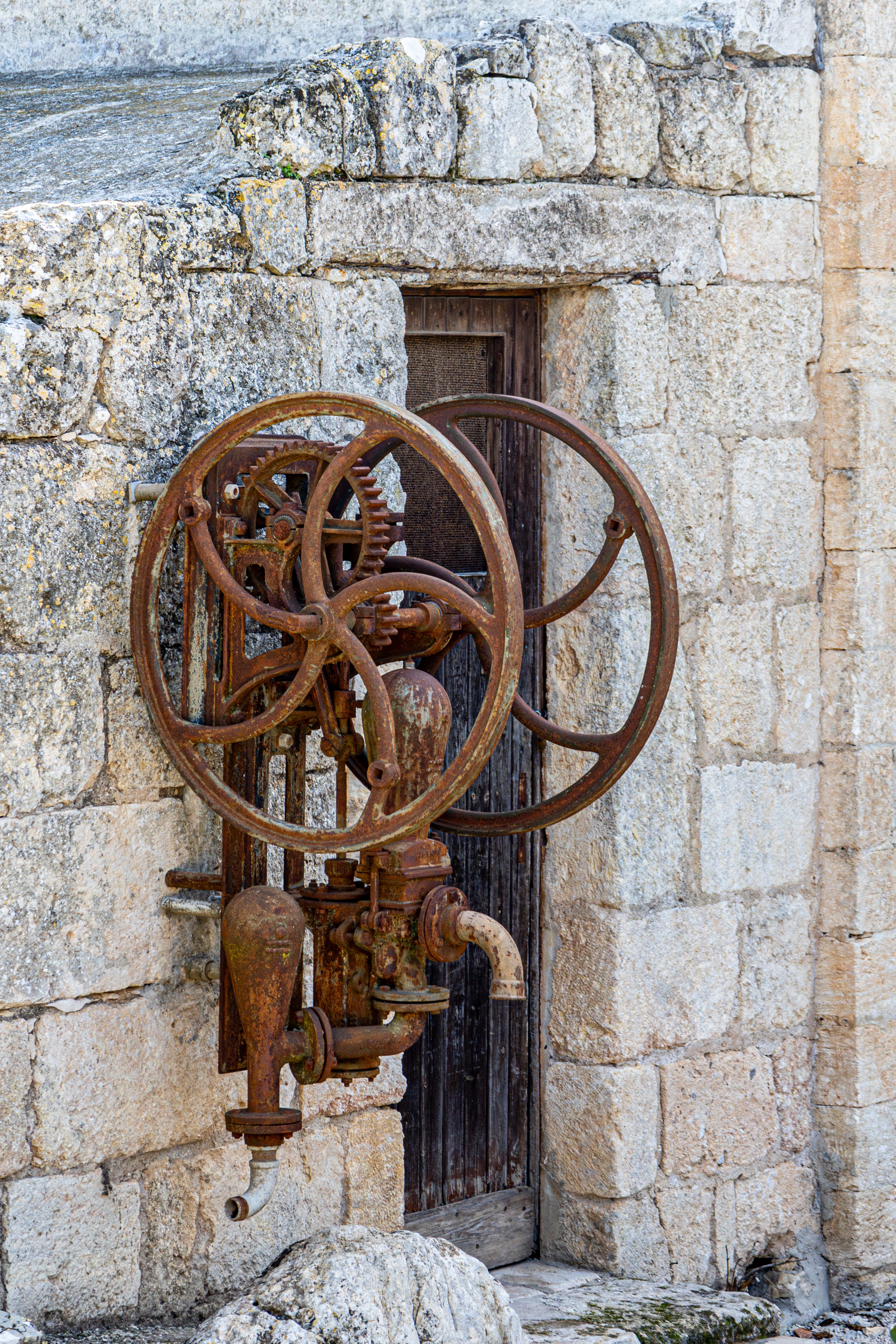 Rusty Ancient Machinery Against Stone Wall · Free Stock Photo
