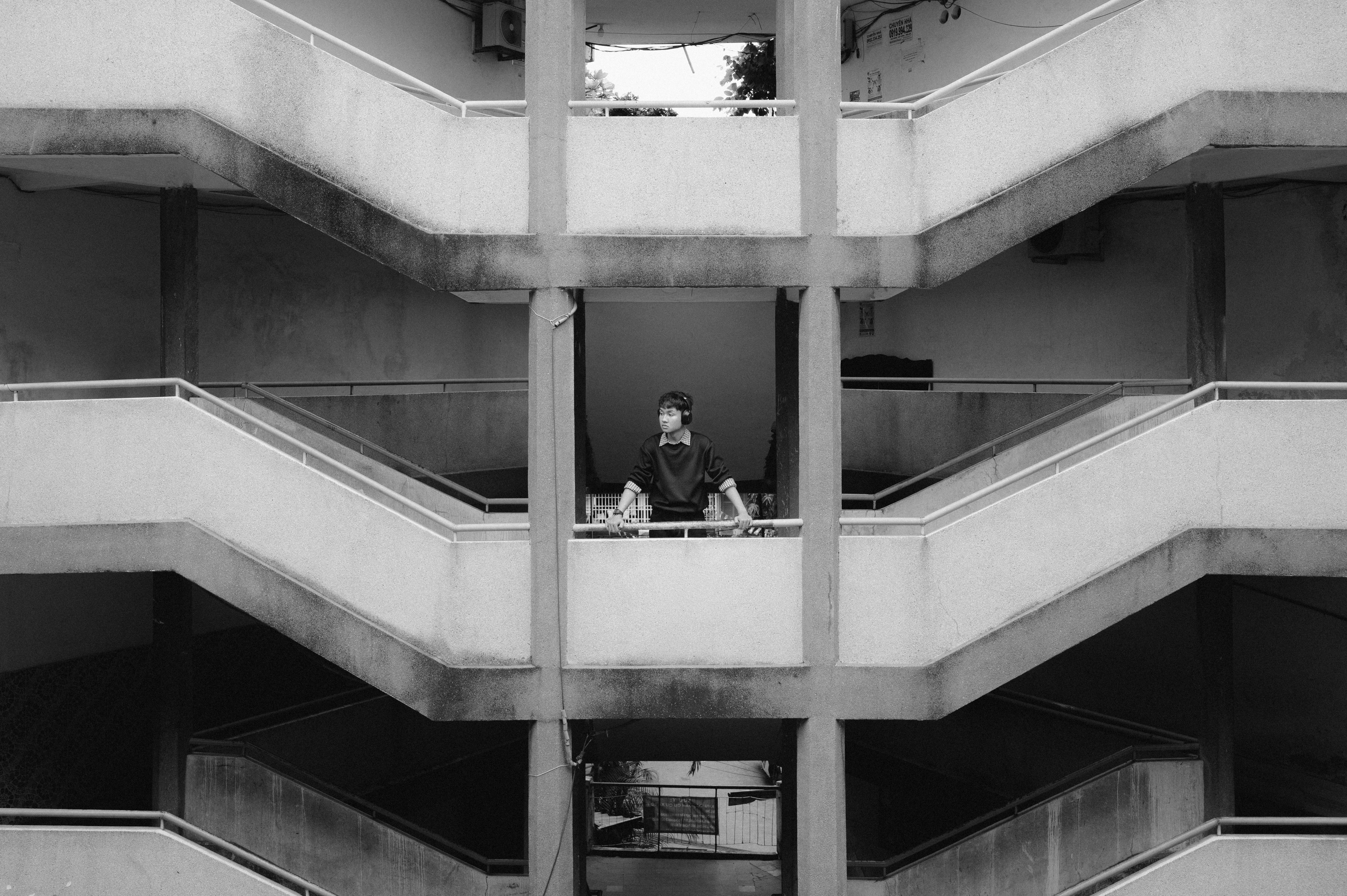 Free A man stands on a concrete staircase in a black and white urban setting. Stock Photo