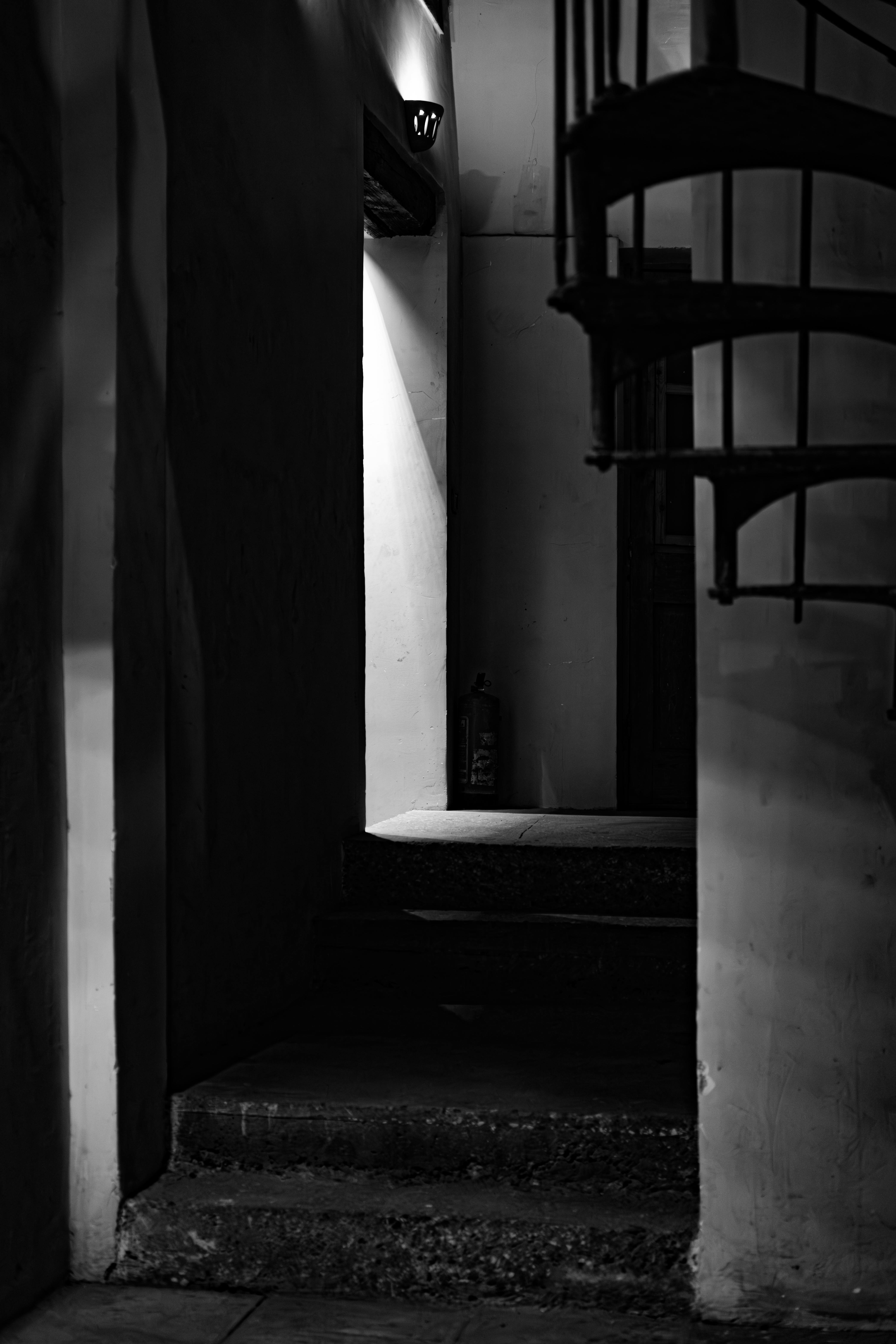 bezplatná Dramatická černobílá fotografie slabě osvětleného schodiště se spirálovými stíny. Základová fotografie