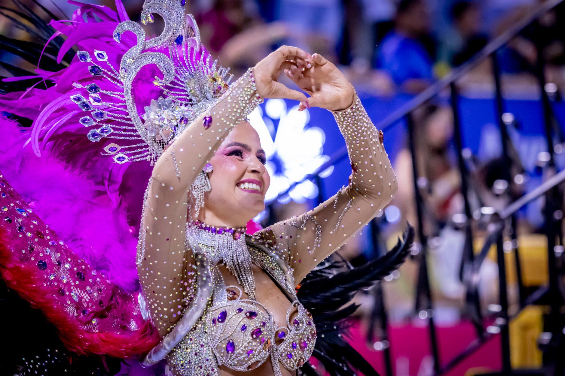 A dancer in colorful costume performs at the Encarnación carnival in Paraguay, showcasing vibrant feathers and intricate designs.