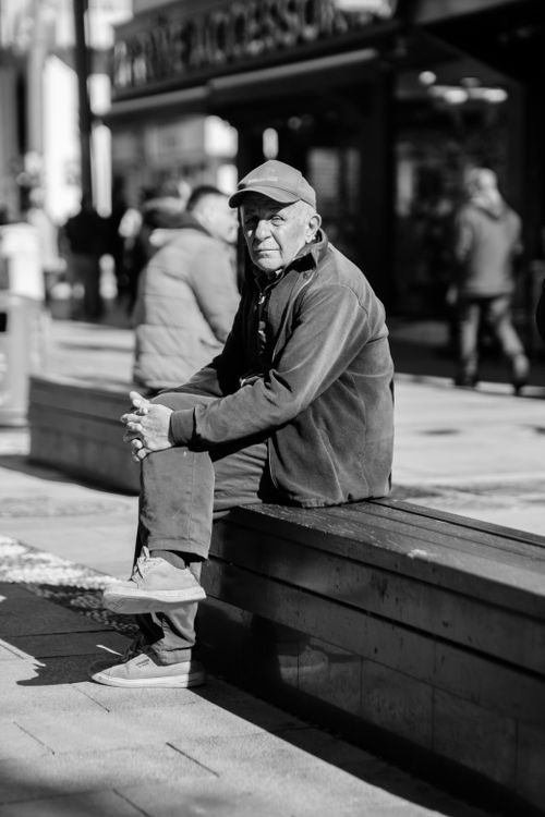 Free Black and white photo of an elderly man sitting on a city bench, conveying solitude and reflection. Stock Photo