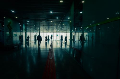 Free Silhouettes in a modern terminal creating a moody atmosphere with reflections on the floor. Stock Photo