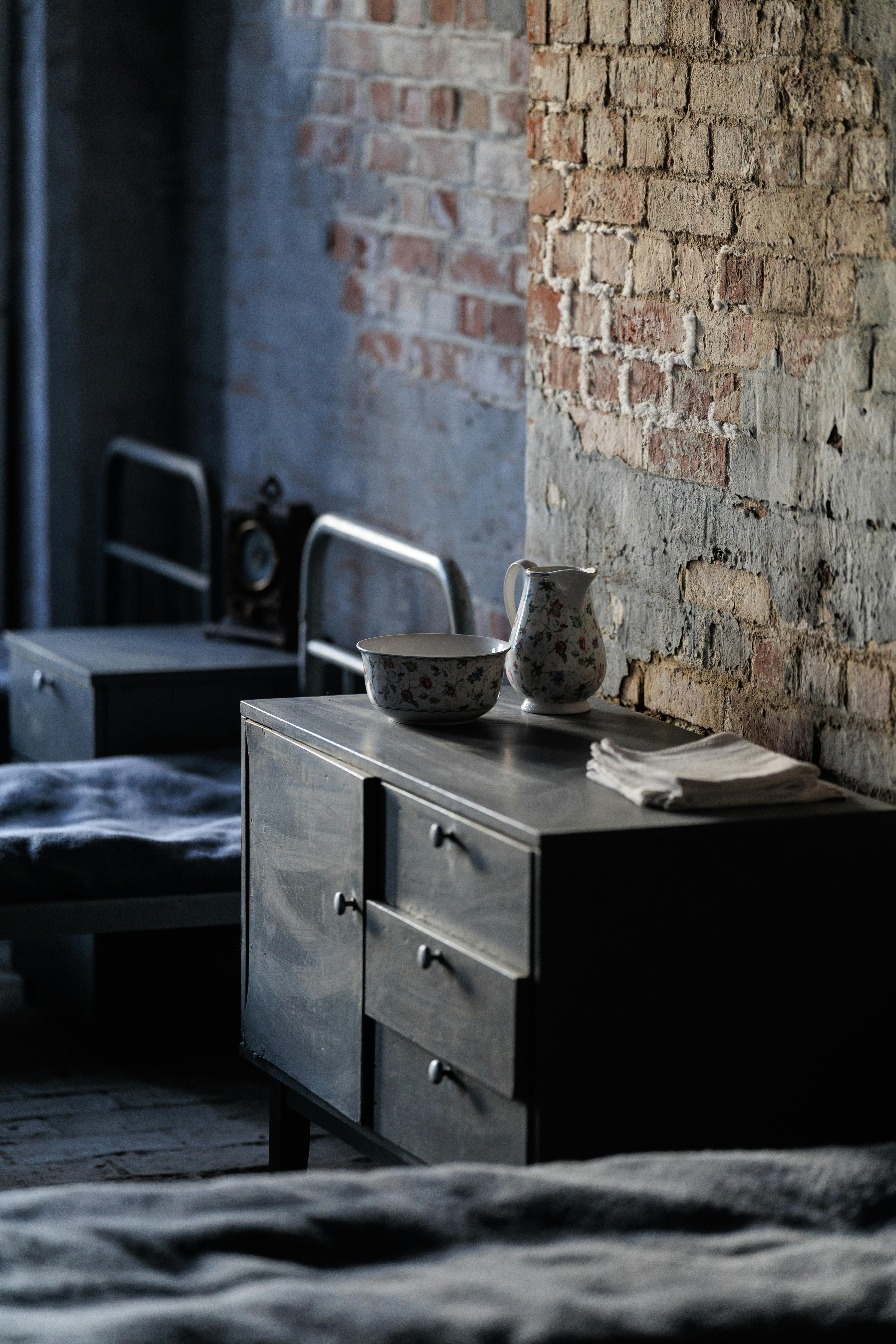 無料 カリーニングラードにある素朴なレンガの壁とアンティーク家具が特徴の雰囲気のあるビンテージ ベッドルーム。 写真素材