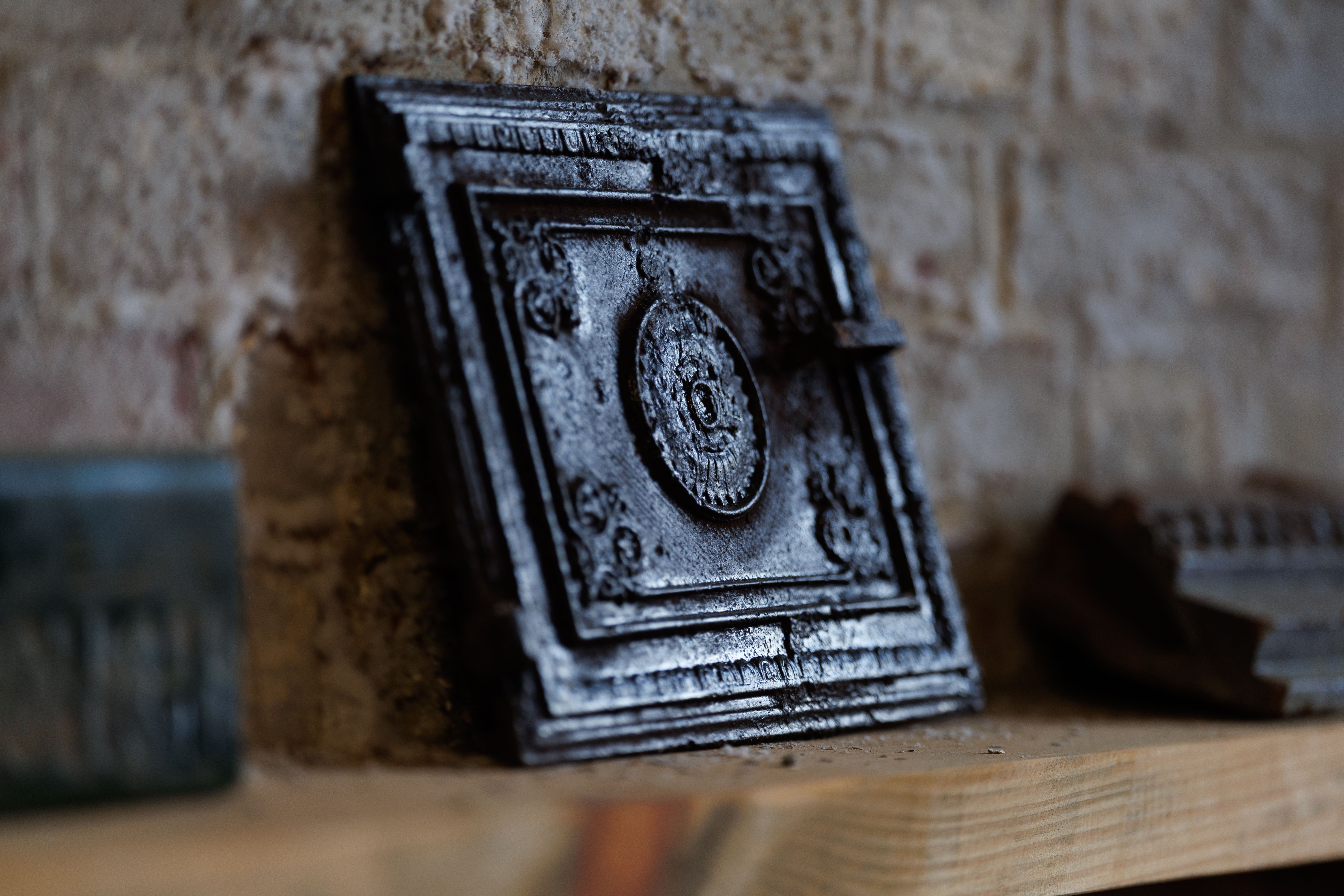 Close-up of a vintage ornate metal furnace door against a rustic brick wall in Kaliningrad, Russia.