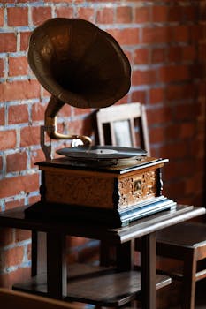 Classic gramophone on wooden table with brick wall backdrop, evoke nostalgia and vintage aesthetics.